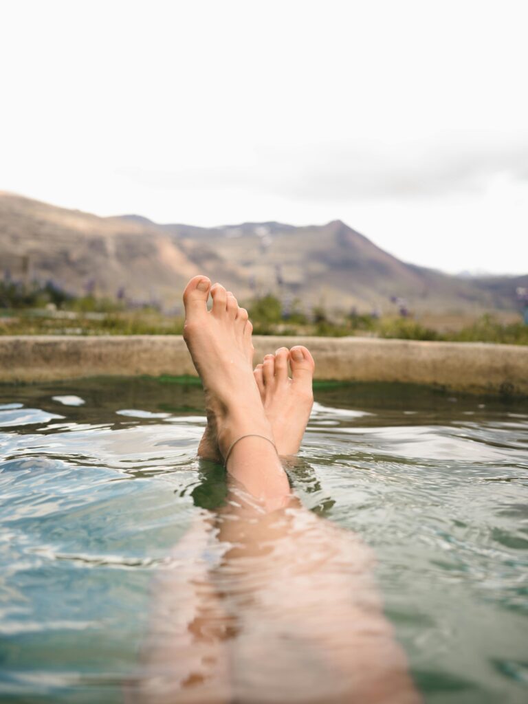 pexels-photo-2755147-2755147 Feet relaxing in a hot spring with a stunning view of Iceland's mountains, perfect for leisure and travel themes.